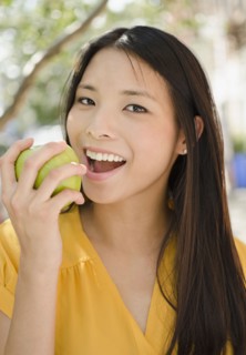 Asian woman eating green apple