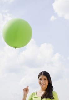 Asian woman holding green balloon