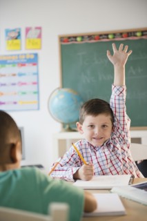 Caucasian boy raising hand in classroom