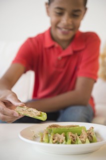 Hispanic boy eating peanut butter on celery