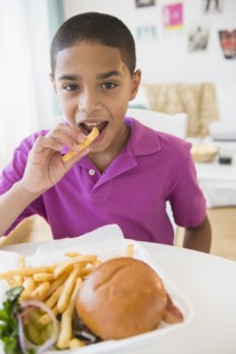 Hispanic boy eating hamburger and french fries