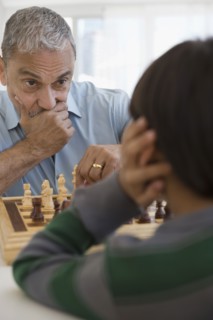 Hispanic grandfather and grandson playing chess