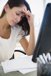 Caucasian businesswoman rubbing forehead at desk