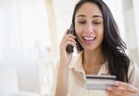 Caucasian woman using credit card on telephone