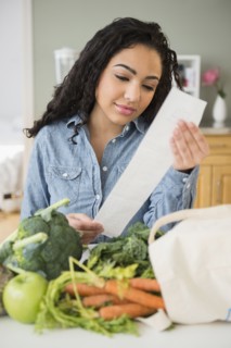 Hispanic woman reading grocery receipt