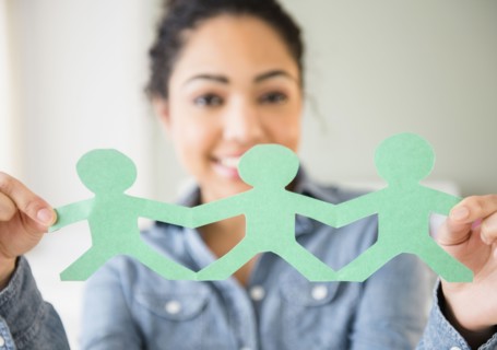 Hispanic woman holding paper dolls