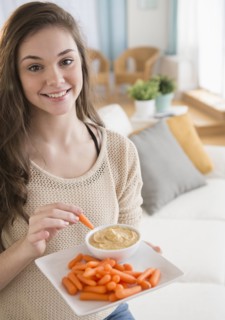 Hispanic girl eating carrots and hummus