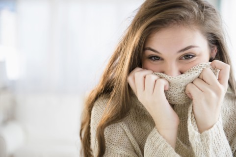Hispanic girl covering her face with sweater