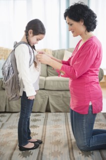 Mother buttoning daughter's sweater in living room