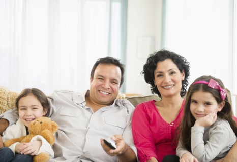 Family watching television together on sofa