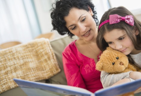 Mother and daughter reading together on sofa