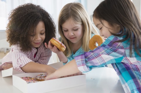 Girls eating donuts together in kitchen