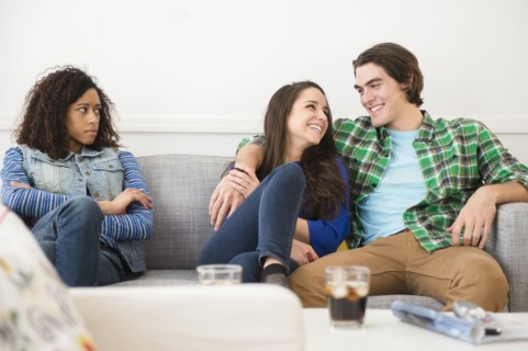 Couple ignoring friend on sofa