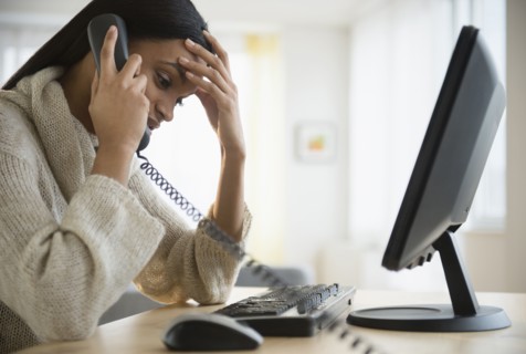 Mixed race woman talking on phone at desk