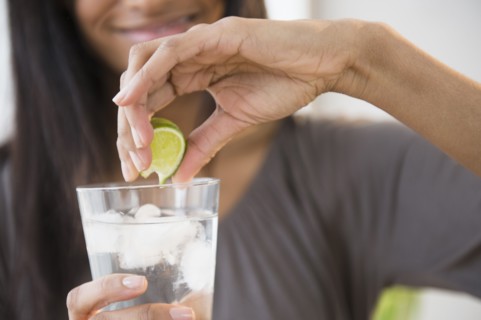 Mixed race woman squeezing lime into drink