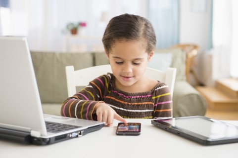 Hispanic girl using cell phone at desk
