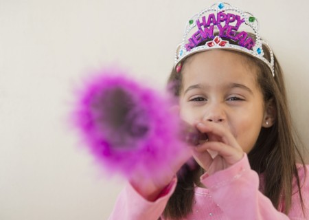 Hispanic girl using noise maker at New Years' party