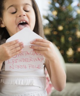 Hispanic girl sealing envelope for Santa