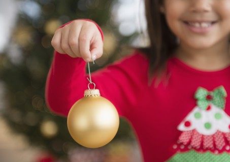 Hispanic girl holding Christmas ornament