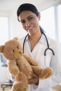Indian doctor holding teddy bear in office