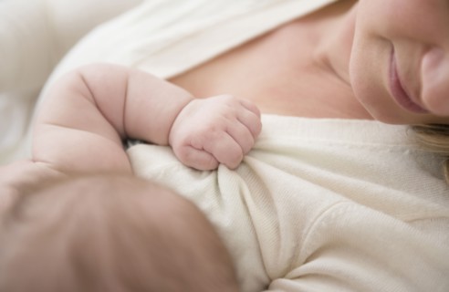 Caucasian baby gripping mother's sweater