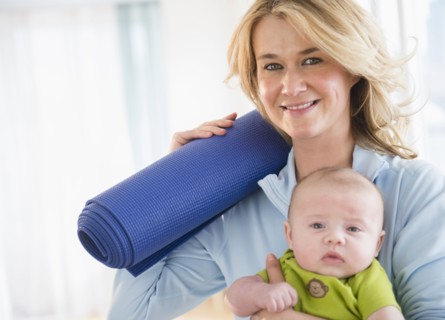 Caucasian mother with baby holding yoga mat