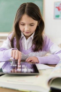 Mixed race girl using tablet computer in class