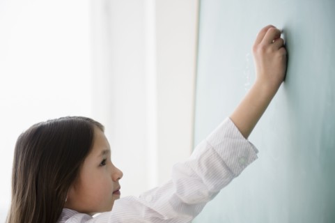 Mixed race girl writing on chalkboard