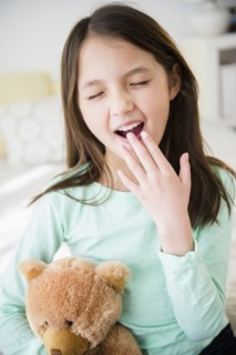 Mixed race girl with teddy bear yawning