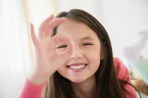 Mixed race girl making O.K. sign with fingers