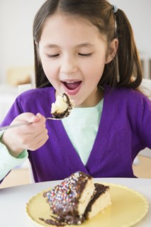 Mixed race girl eating cake
