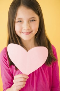 Mixed race girl holding heart