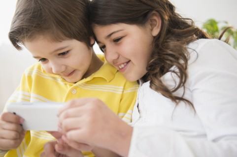 Hispanic children using cell phone together