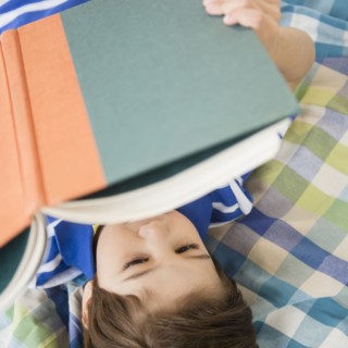 Hispanic boy reading on bed