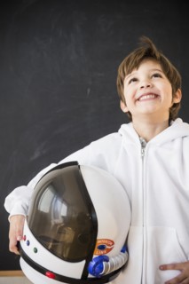Hispanic boy holding space helmet in classroom