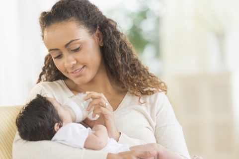Hispanic mother bottle feeding infant son