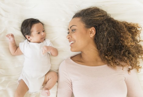 Hispanic mother and infant laying on bed