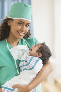 Hispanic doctor holding newborn in hospital