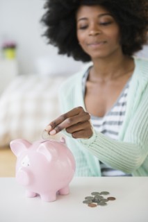 Mixed race woman putting coins in piggy bank