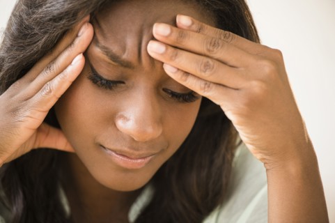 Black woman frowning with head in hands