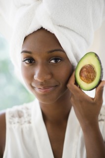 Black woman holding sliced avocado