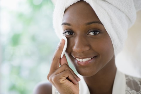 Black woman wiping face with cotton pad