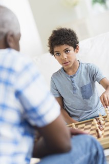Boy playing chess with grandfather