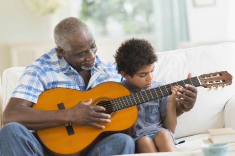 Boy playing guitar with grandfather