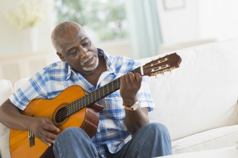 Black man playing guitar on sofa