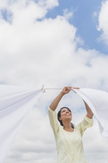Black woman hanging sheets from clothesline