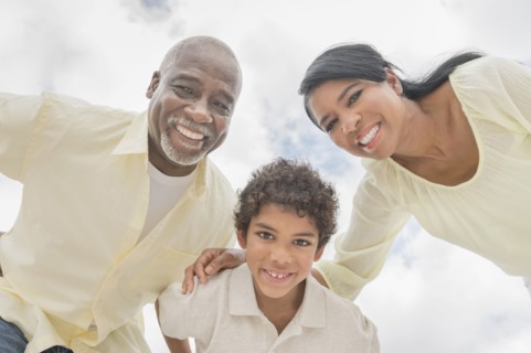 Three generations of family smiling in huddle outdoors