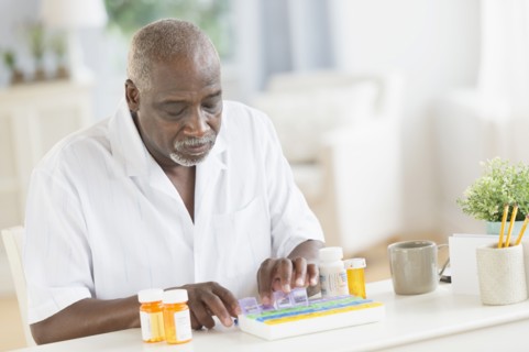 Black man counting pills in pill boxes