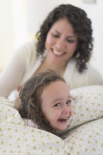 Mixed race mother putting daughter to bed