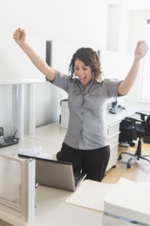 Hispanic businesswoman cheering in office